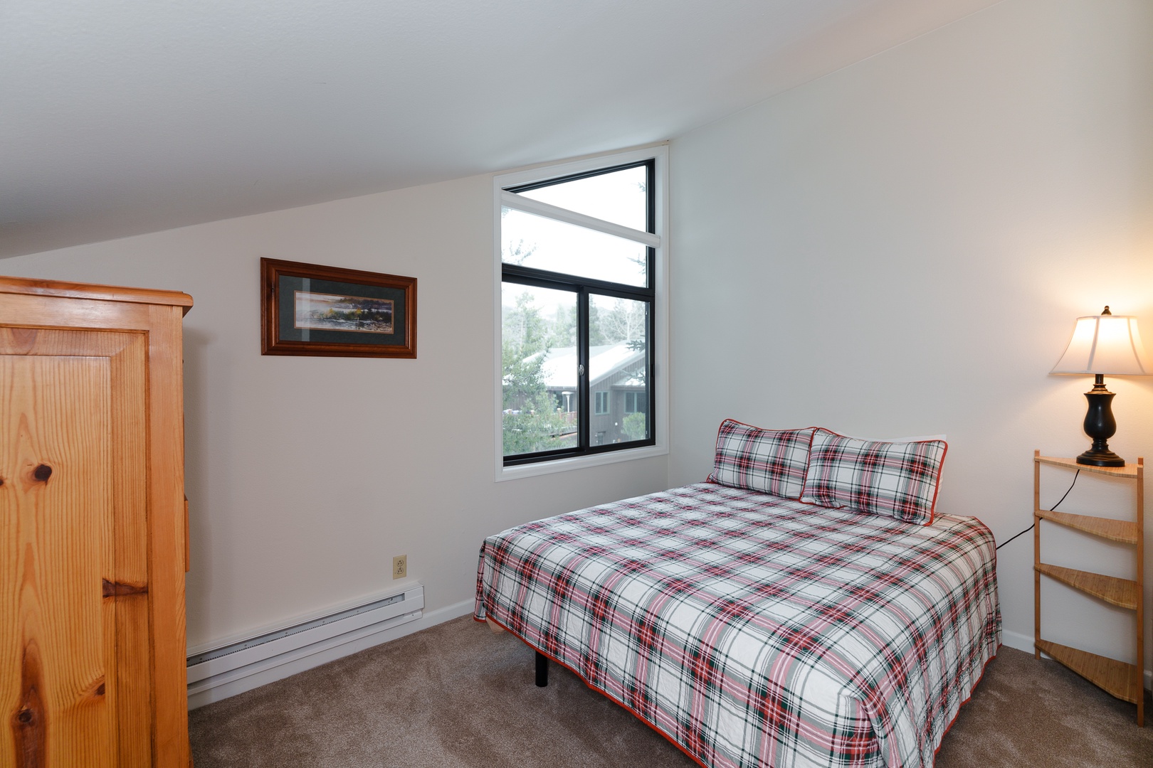 Cozy bedroom with plaid bedding and natural light streaming through your window, featuring warm wood furnishings and a peaceful atmosphere for restful nights.