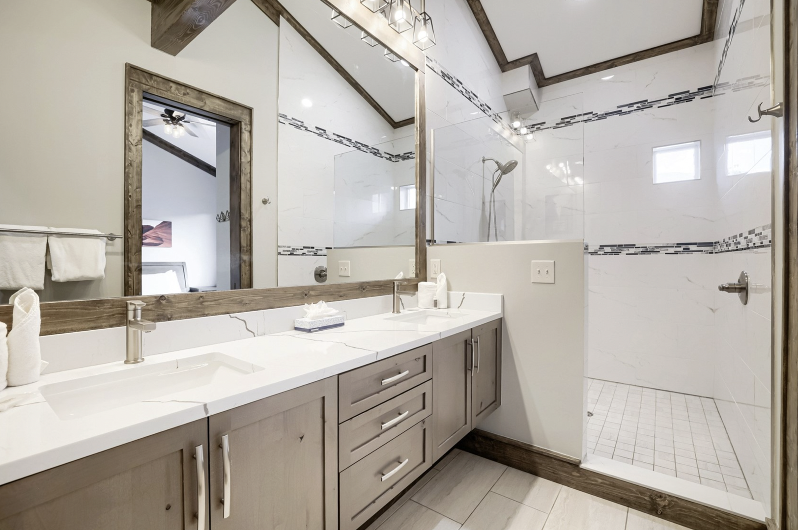 Step into your serene spa-style bathroom, where gleaming white countertops and a spacious walk-in shower await. Vaulted ceilings and rustic wood accents create a bright, airy retreat after your adventures.