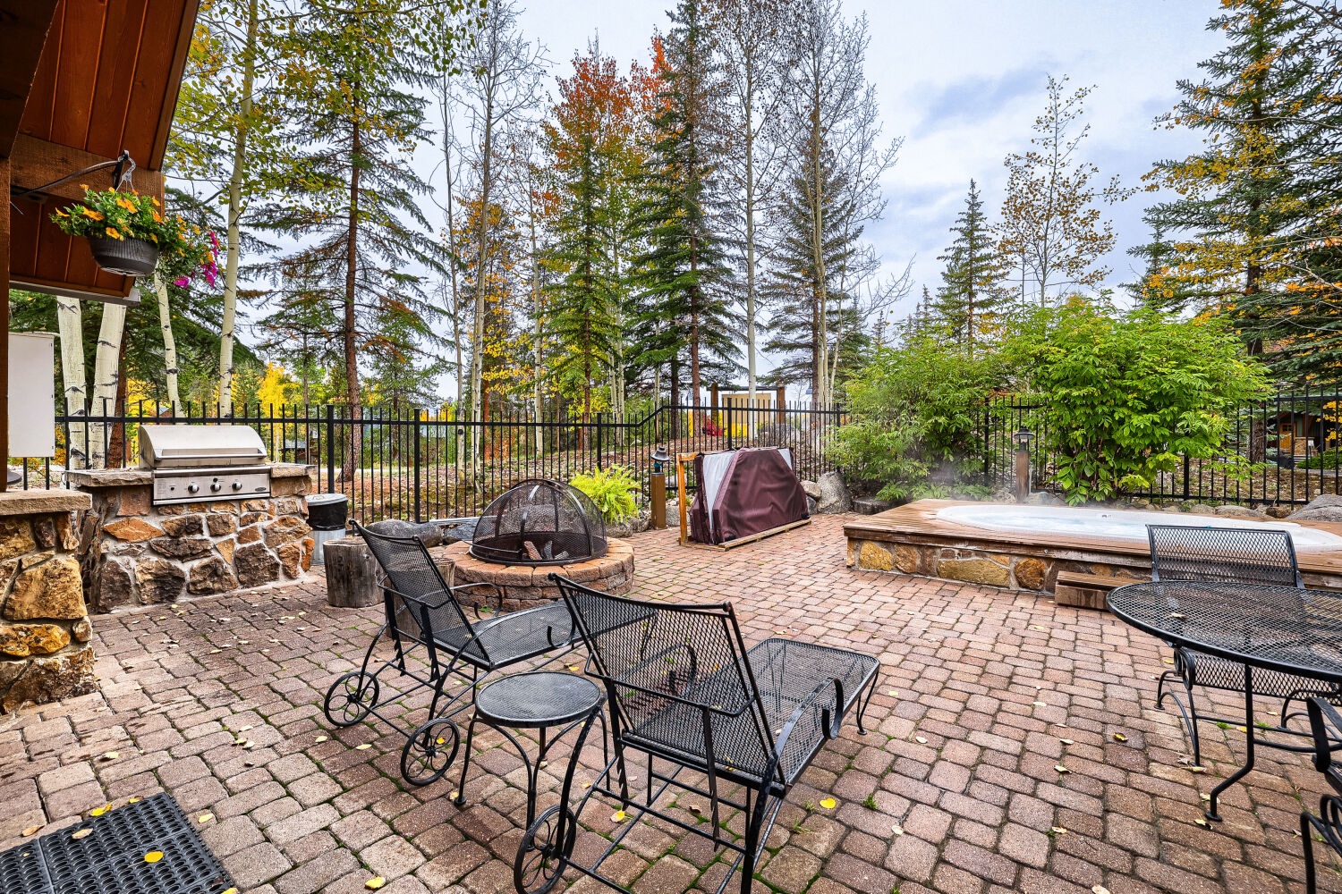 Your private outdoor retreat features a spacious patio with a built-in grill, crackling fire pit, and steaming hot tub—all surrounded by towering pines and autumn foliage.