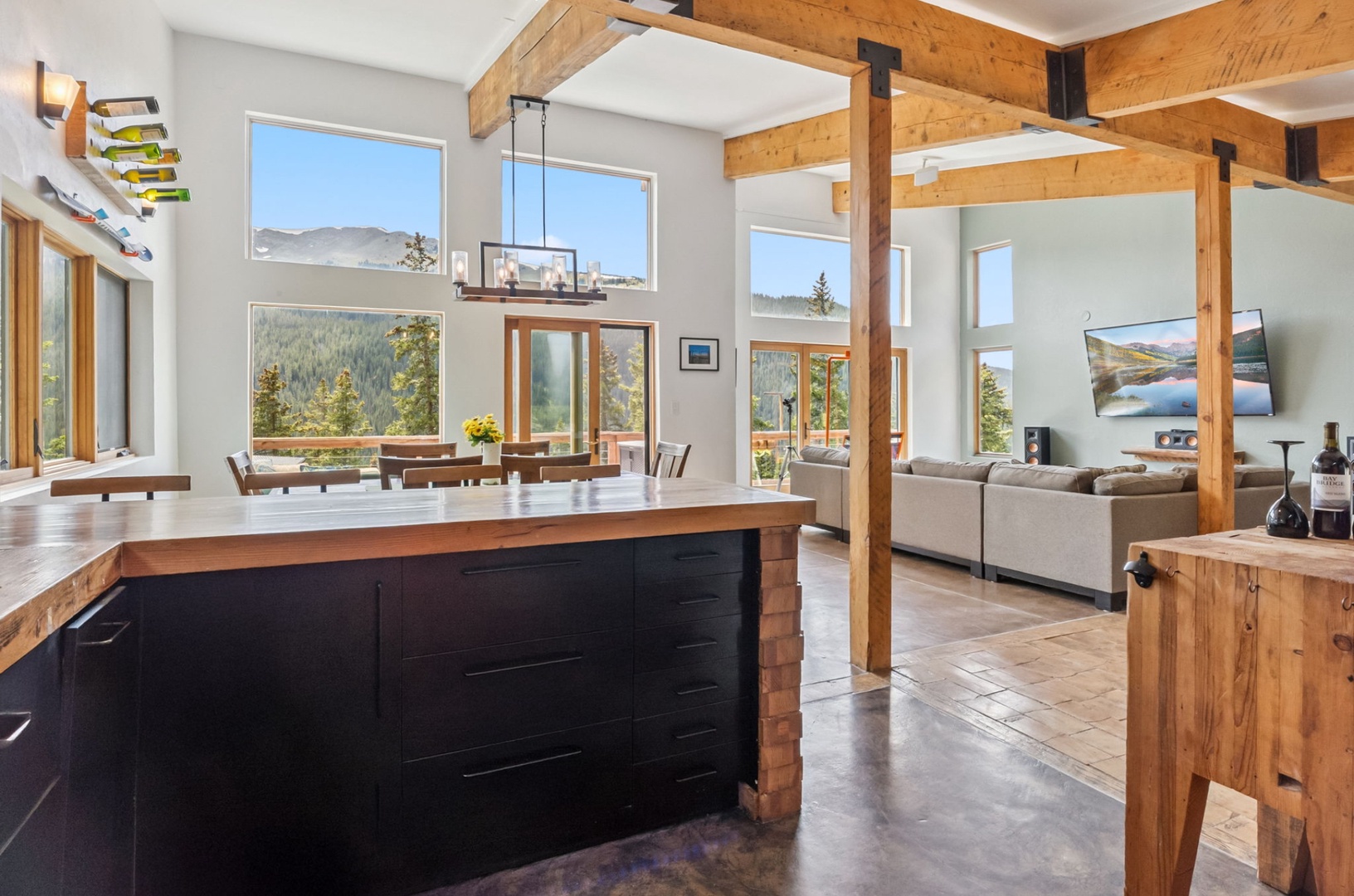 Sunlight pours through expansive windows, framing stunning mountain views as you gather in this open-concept space with exposed beams, a chef's island, and cozy lounge seating.
