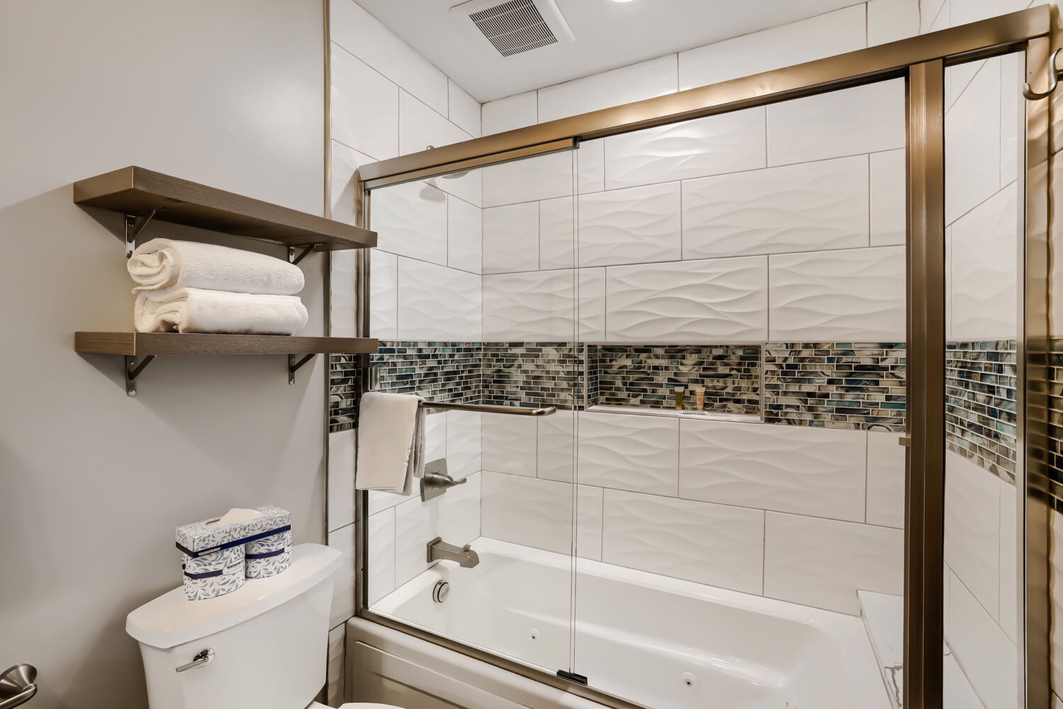 Slip into relaxation with a soak in your gleaming tub or rinse off under the glass-enclosed shower, all framed by elegant bronze finishes and thoughtful mosaic tilework.