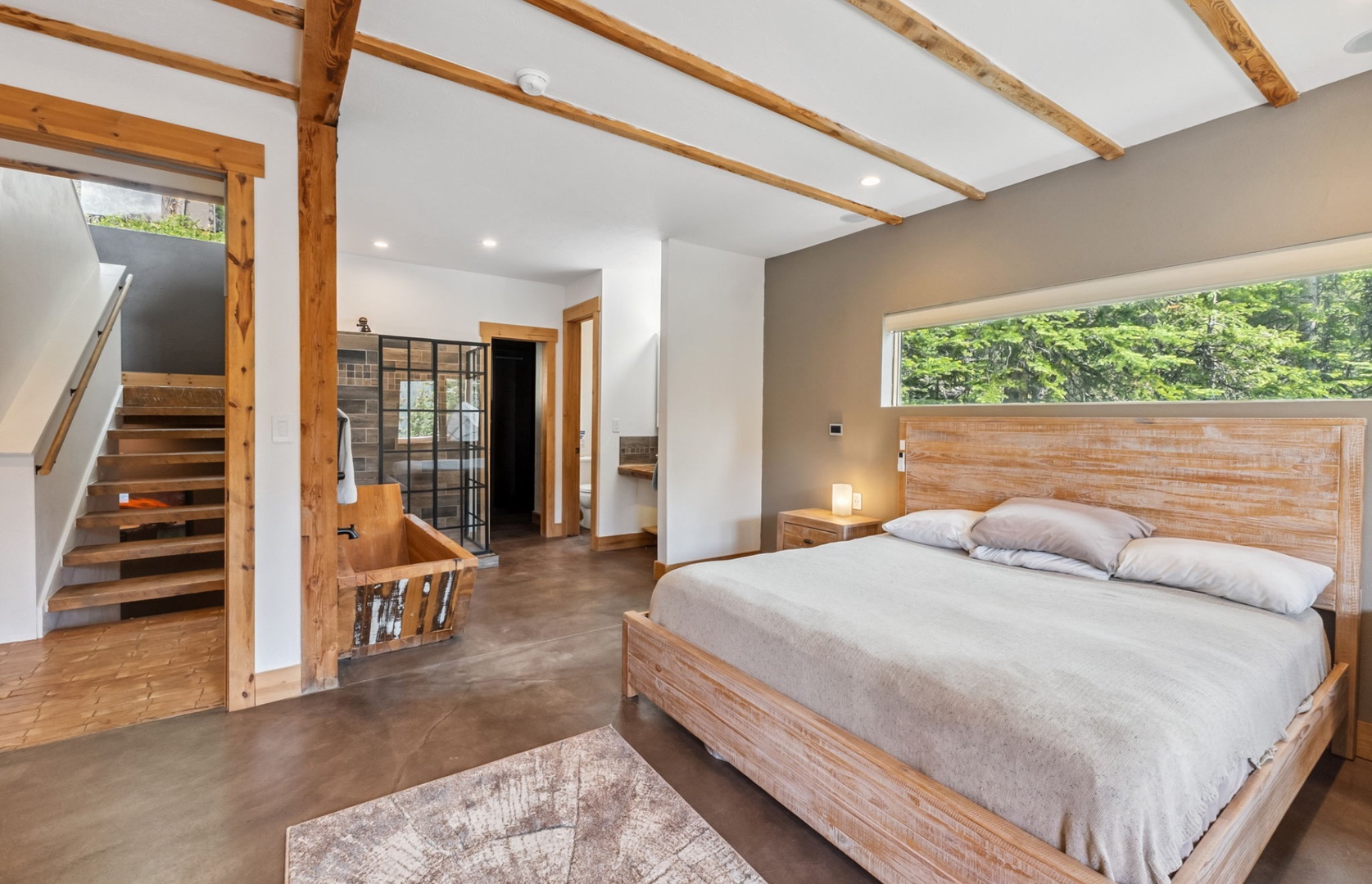 Unwind in your serene bedroom with exposed wooden beams, a plush king bed, and a peaceful garden view that invites morning light to gently wake you.