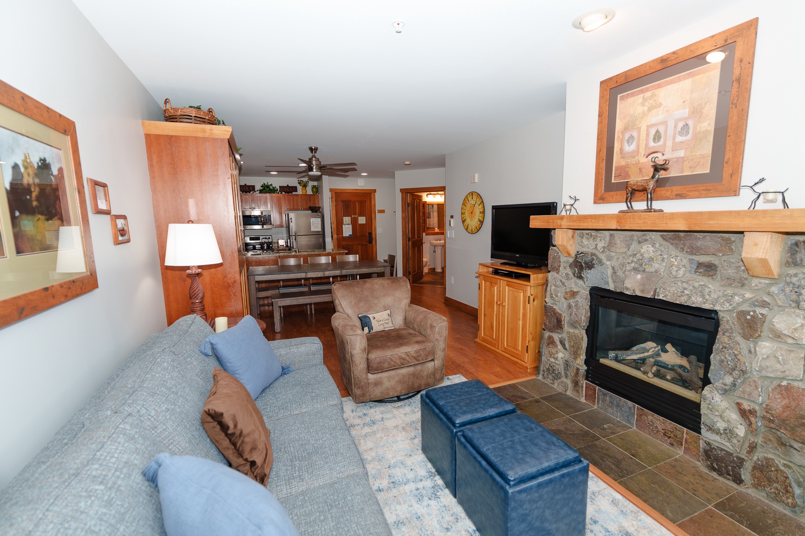 Relax by your stone fireplace in this inviting living room, complete with comfortable seating and seamless flow to the fully equipped kitchen.