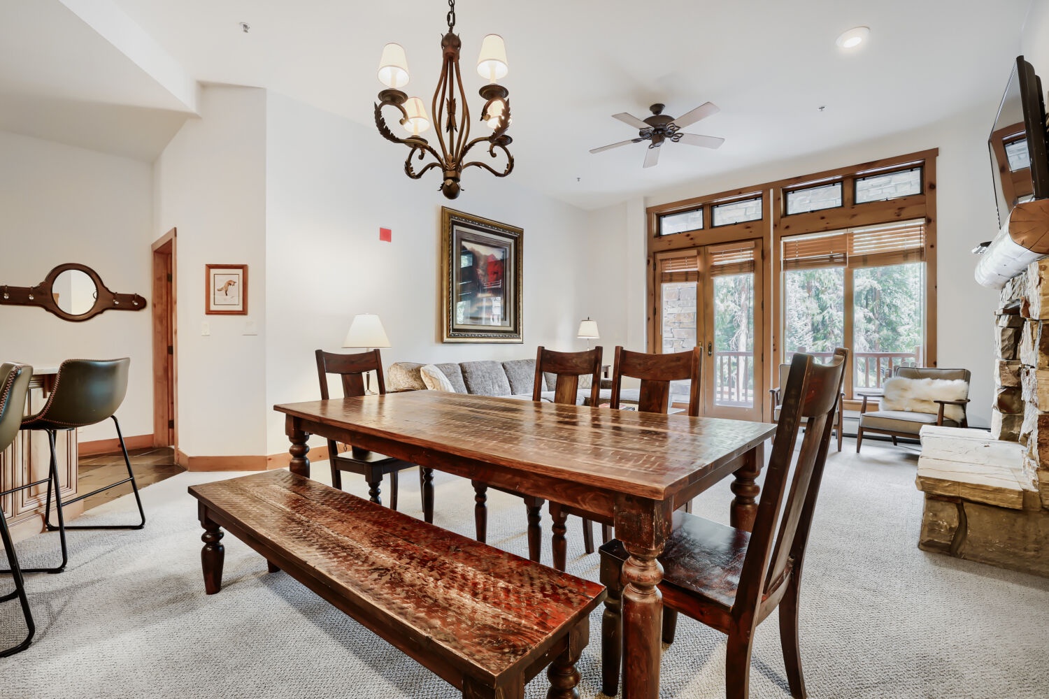 Gather around the handcrafted wood table for meals with friends and family. Large windows frame views of the surrounding trees, while the open layout connects you to the cozy living area.