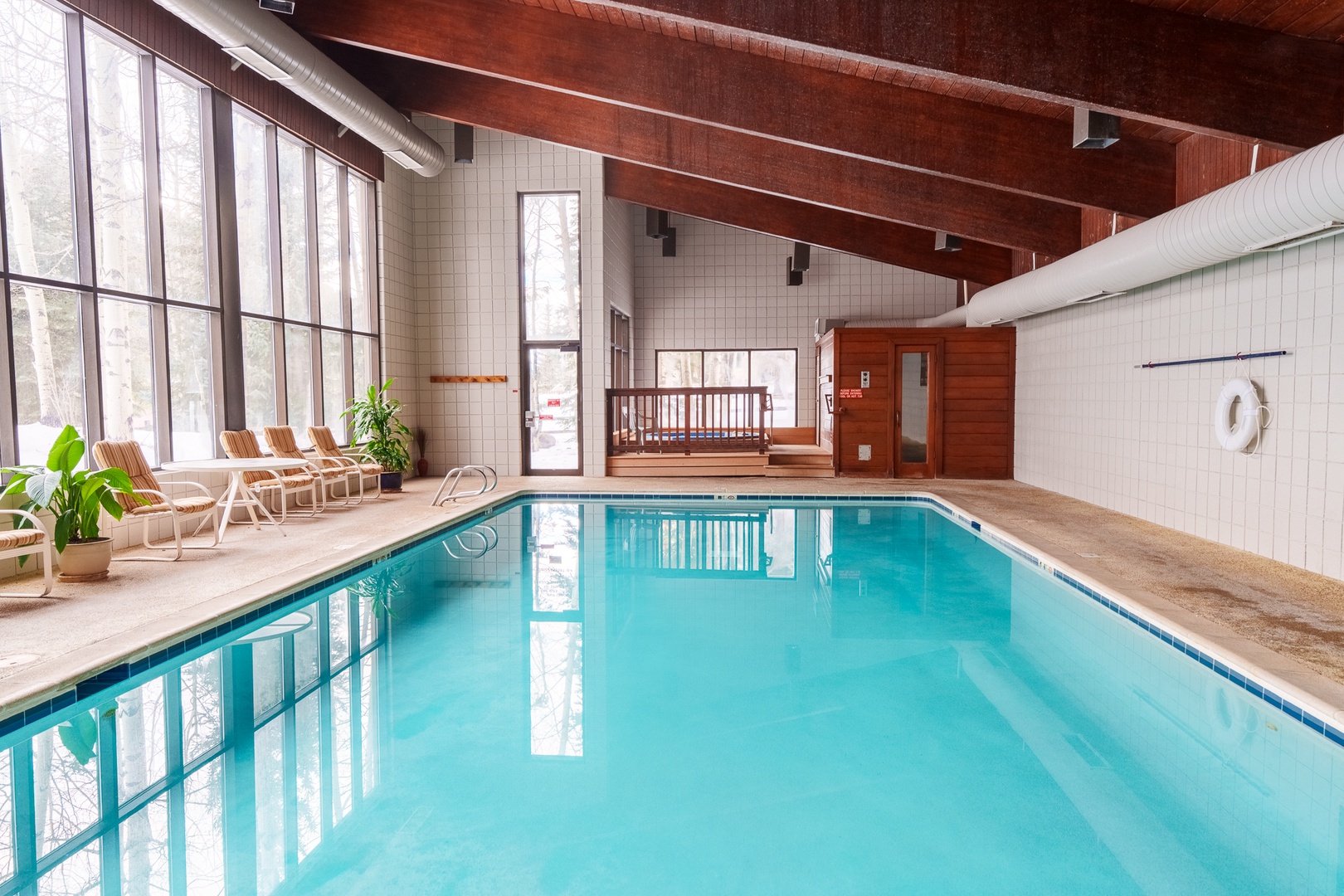 Dive into crystal-clear waters in your private indoor pool, surrounded by warm wood beams and natural light streaming through floor-to-ceiling windows.