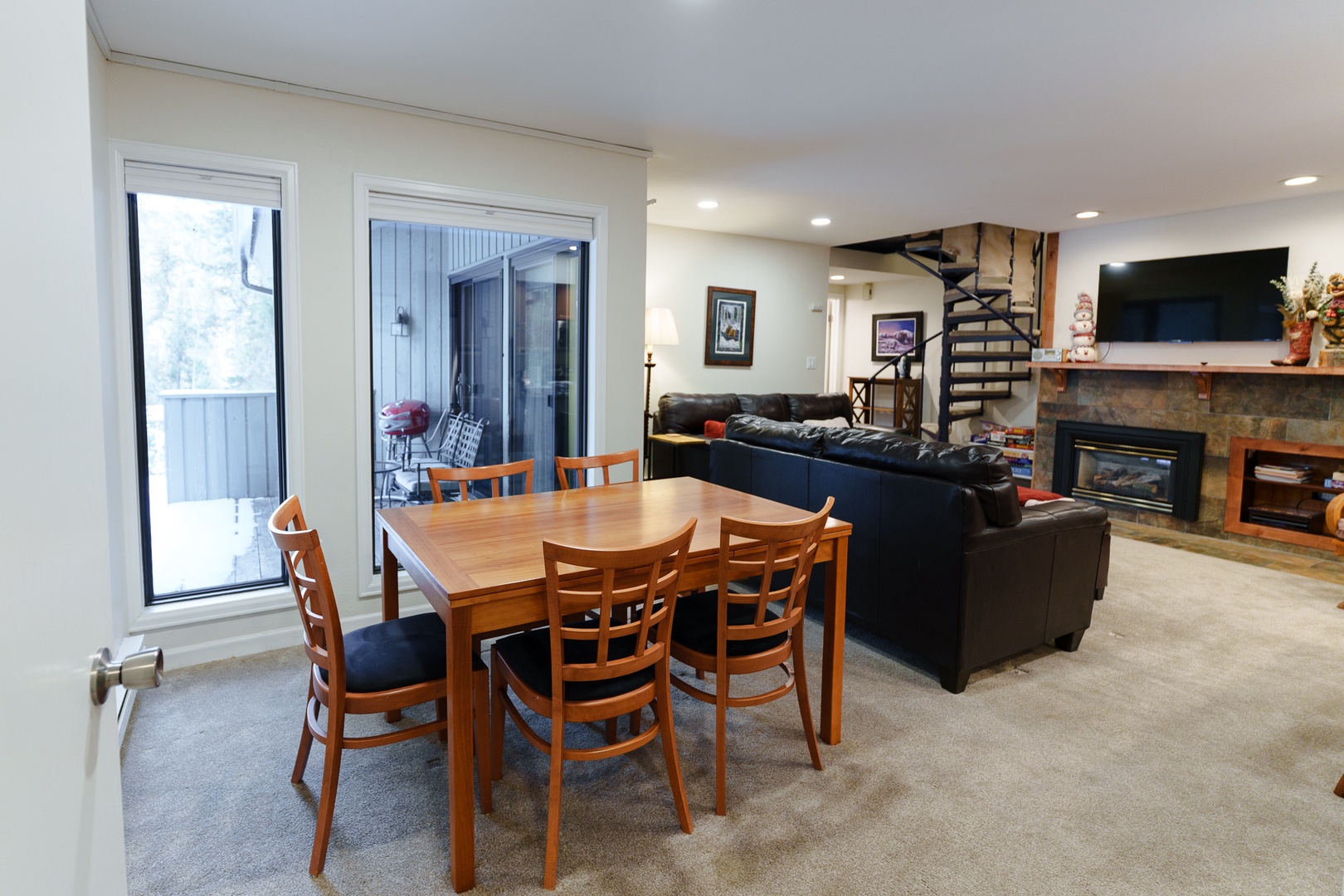 Your spacious living area seamlessly blends dining and relaxation with a warm stone fireplace, comfortable leather seating, and access to your private balcony.