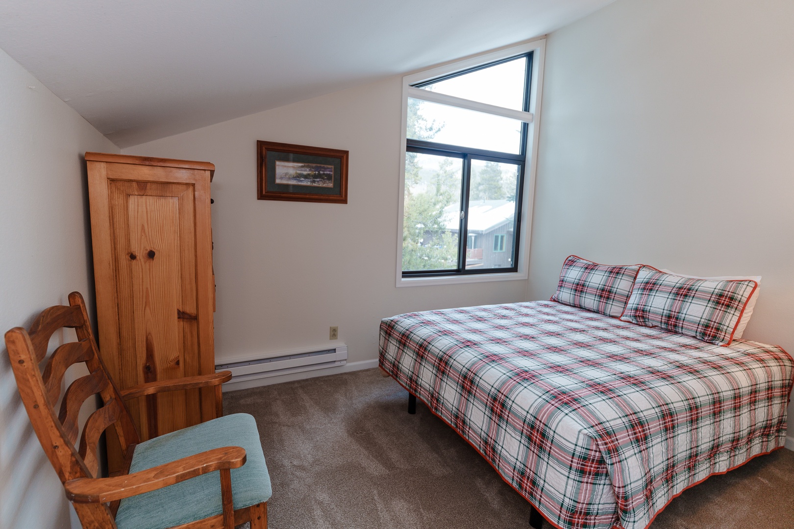 Cozy bedroom with plaid bedding, natural wood furnishings, and a peaceful view from your window.