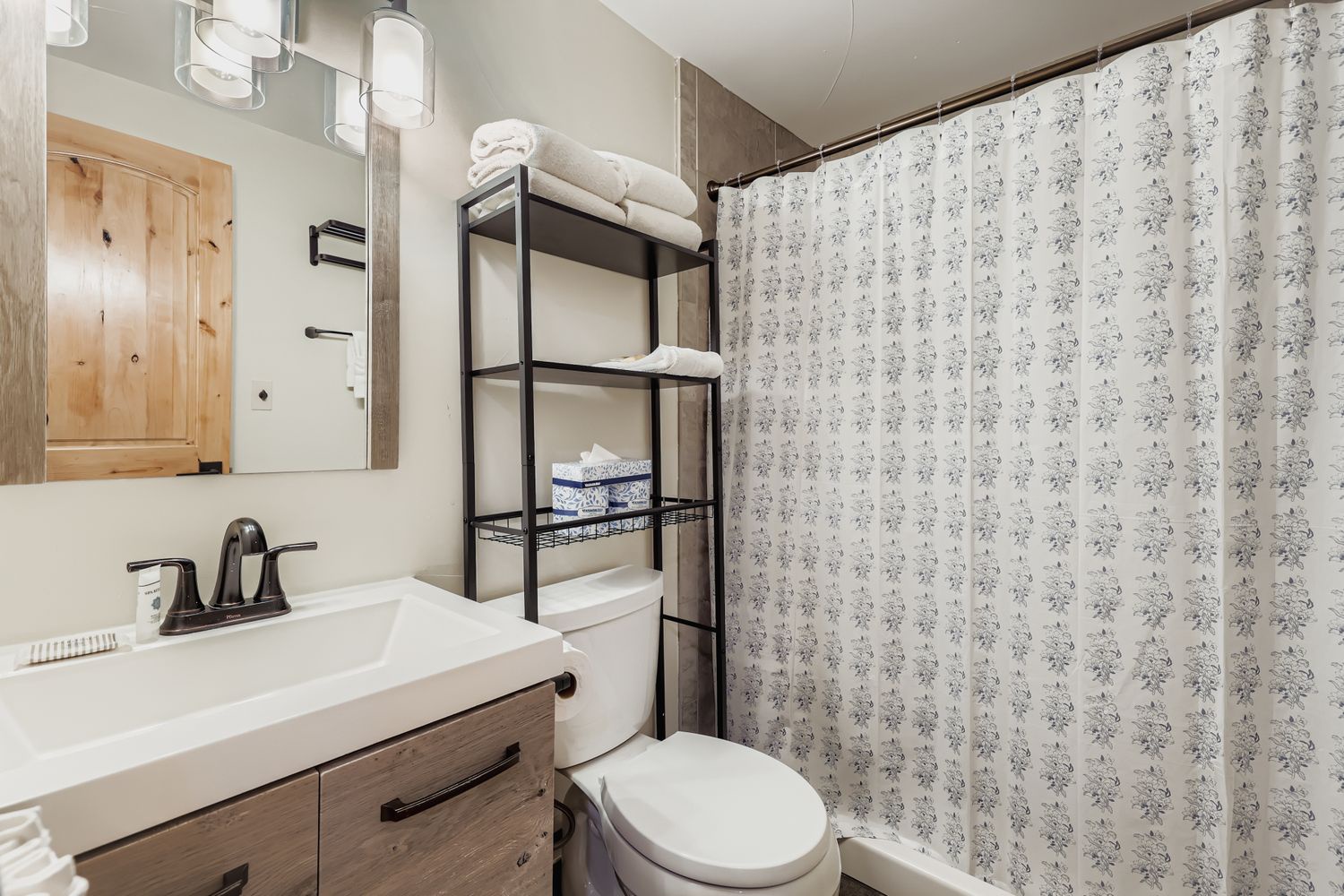 Refresh in your stylish bathroom featuring a modern vanity, rainfall shower, and thoughtful storage for all your essentials during your stay.