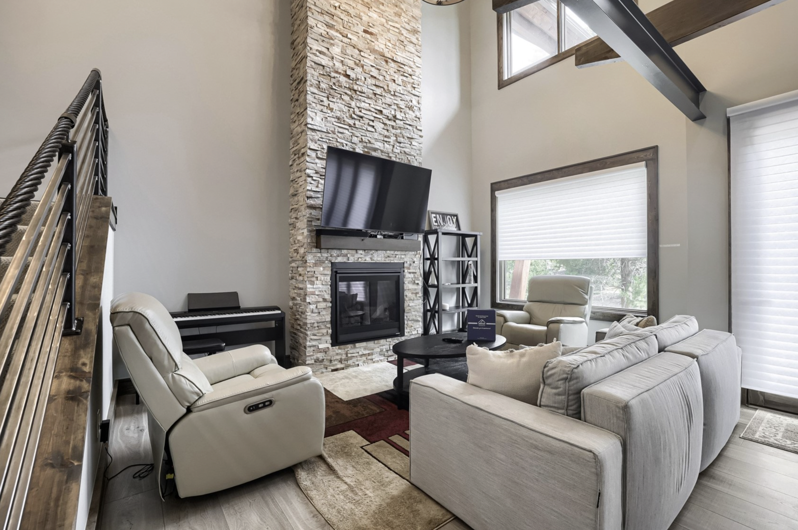 Your spacious living room welcomes you with soaring ceilings, plush seating arranged around a striking stone fireplace, and sunlight streaming through tall windows—perfect for relaxing after a day of adventure.