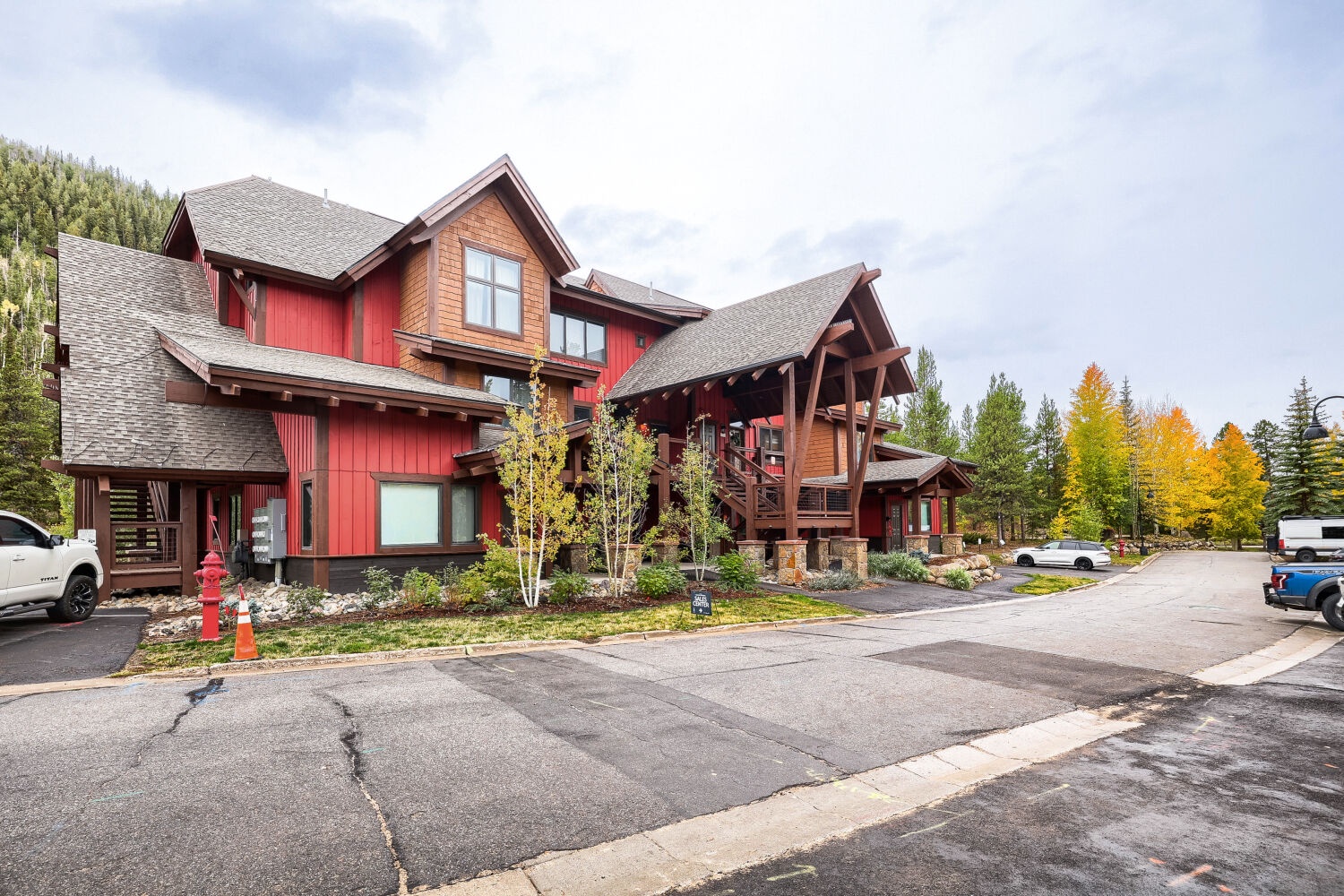 A striking red and timber lodge-style building set against forested hillsides, with vibrant autumn foliage adding seasonal color to the mountain surroundings.