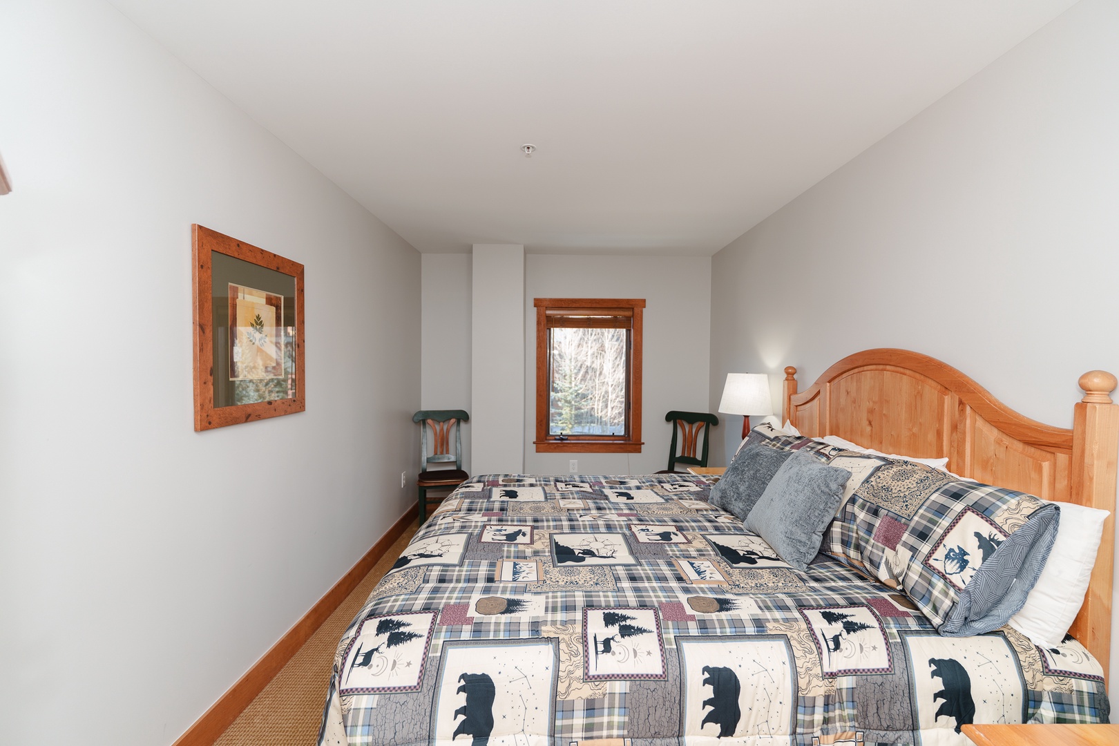 Cozy bedroom with rustic charm featuring a comfortable bed dressed in wilderness-themed bedding and warm wood accents for your mountain getaway.
