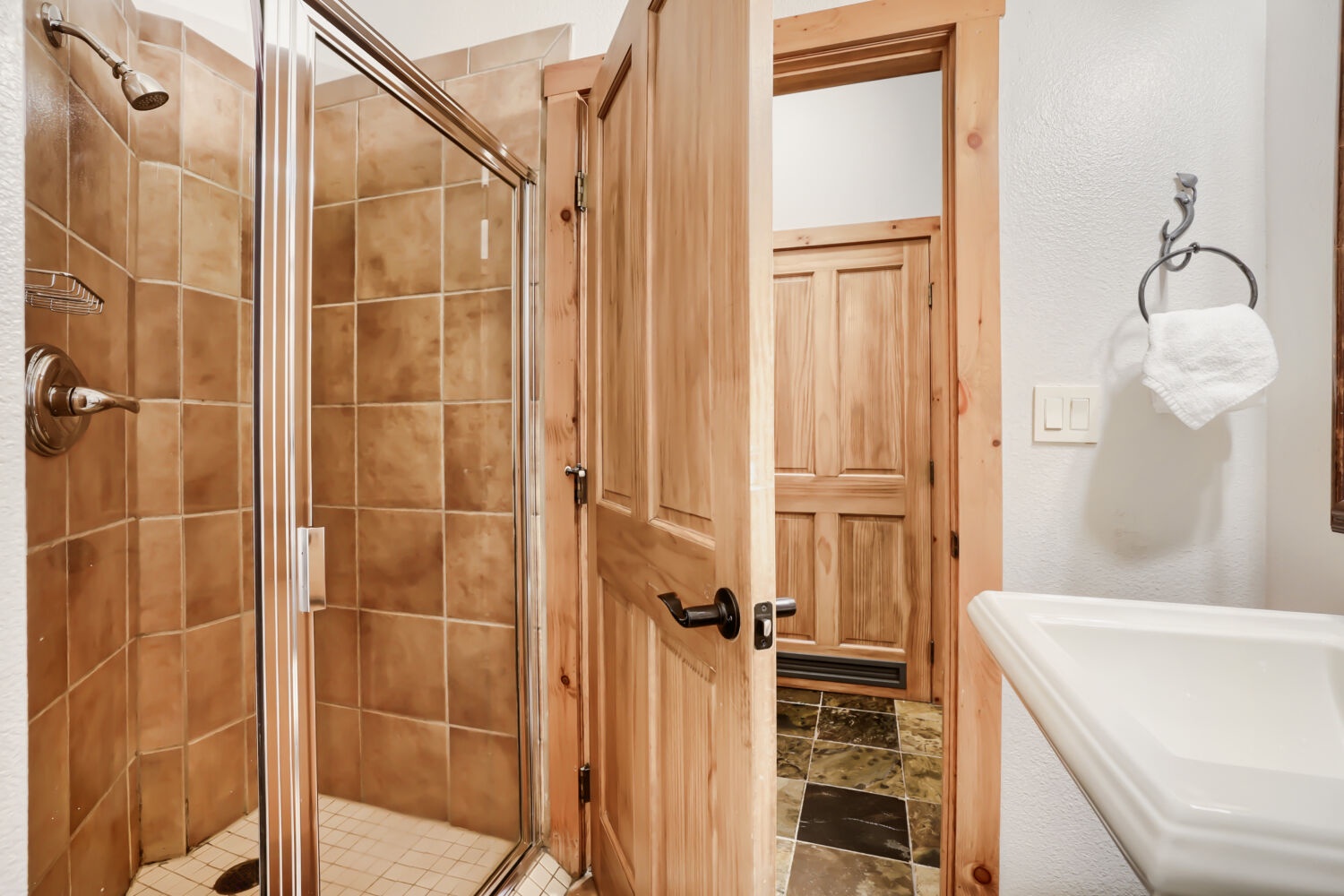 Step into your private bathroom featuring warm tile, a glass-enclosed shower, and fresh towels waiting for you—rustic wood accents throughout create a cozy, cabin-like retreat.