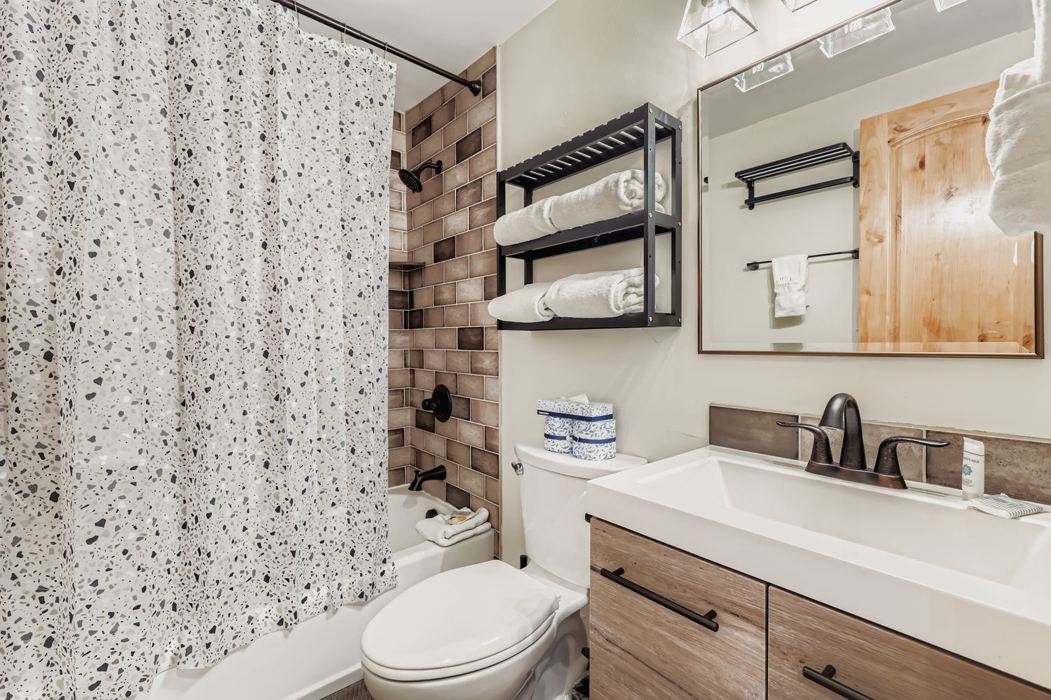 Step into your stylish bathroom featuring modern terrazzo walls, elegant tile details, and thoughtful storage with fresh towels ready for your comfort.