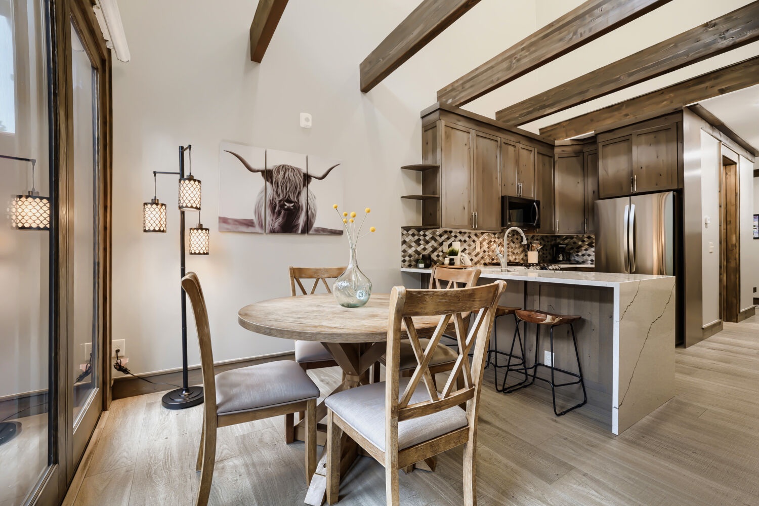 Gather around a rustic dining table under stunning exposed beams, then chat over coffee at the breakfast bar in this open, mountain-inspired kitchen space.