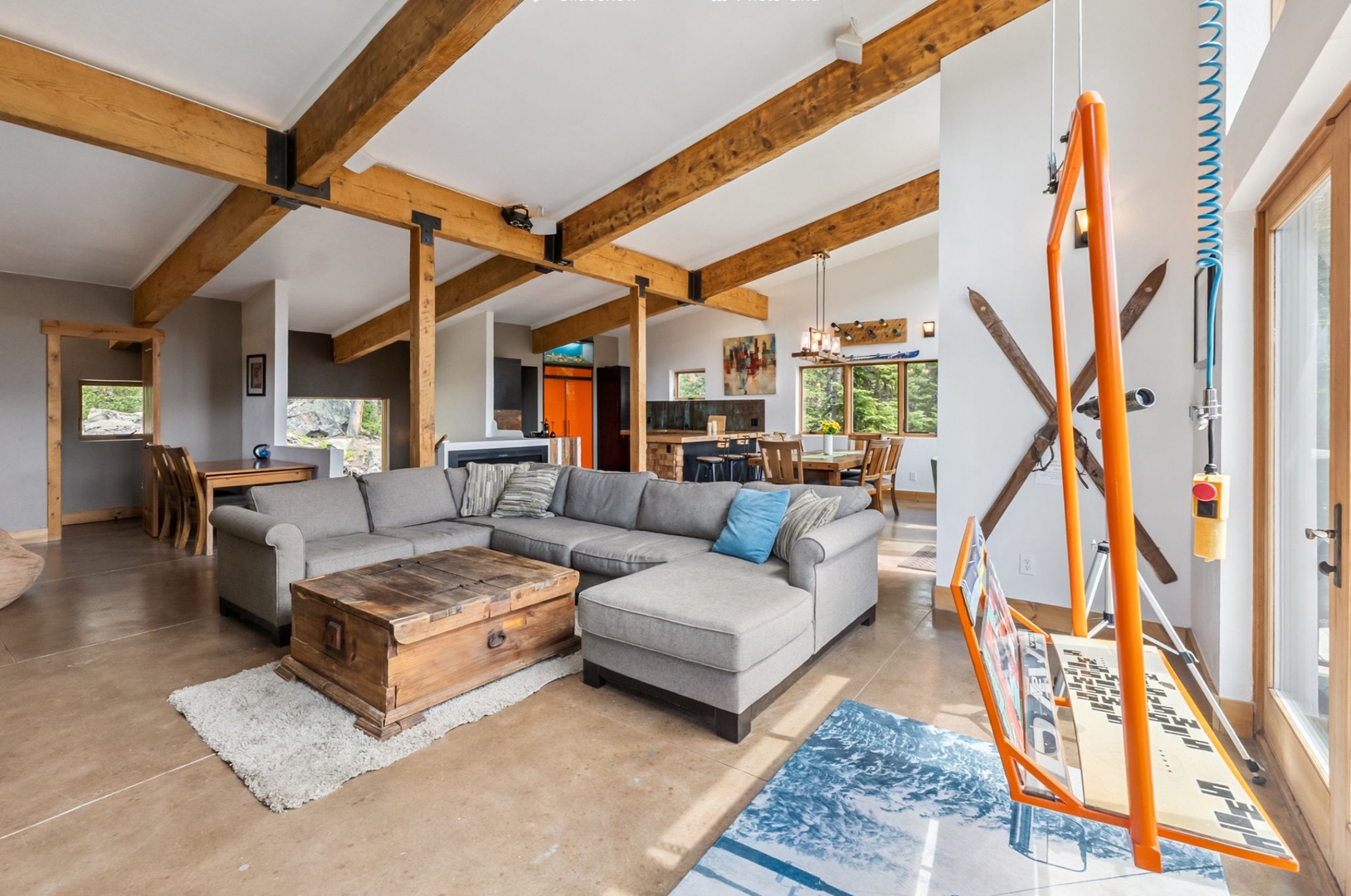 Unwind in your spacious open-plan living area featuring soaring beamed ceilings, plush sectional seating, and natural light streaming through large windows. Cozy up with loved ones in this inviting mountain retreat.