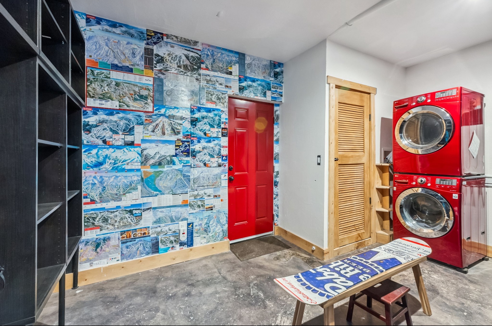 Your laundry day just got cooler—literally. Stacked red washers and dryers make chores easy while ski trail maps set a playful mountain mood. Racks await your gear; adventure starts here.