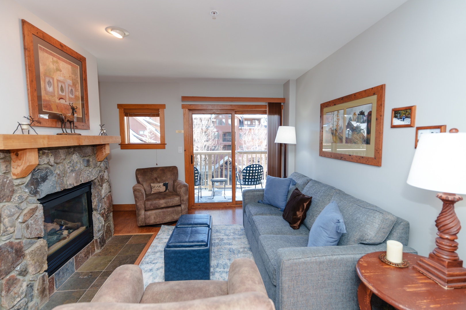 Relax in your cozy living room with comfortable seating around the stone fireplace, where warm wood accents and mountain views create the perfect retreat.