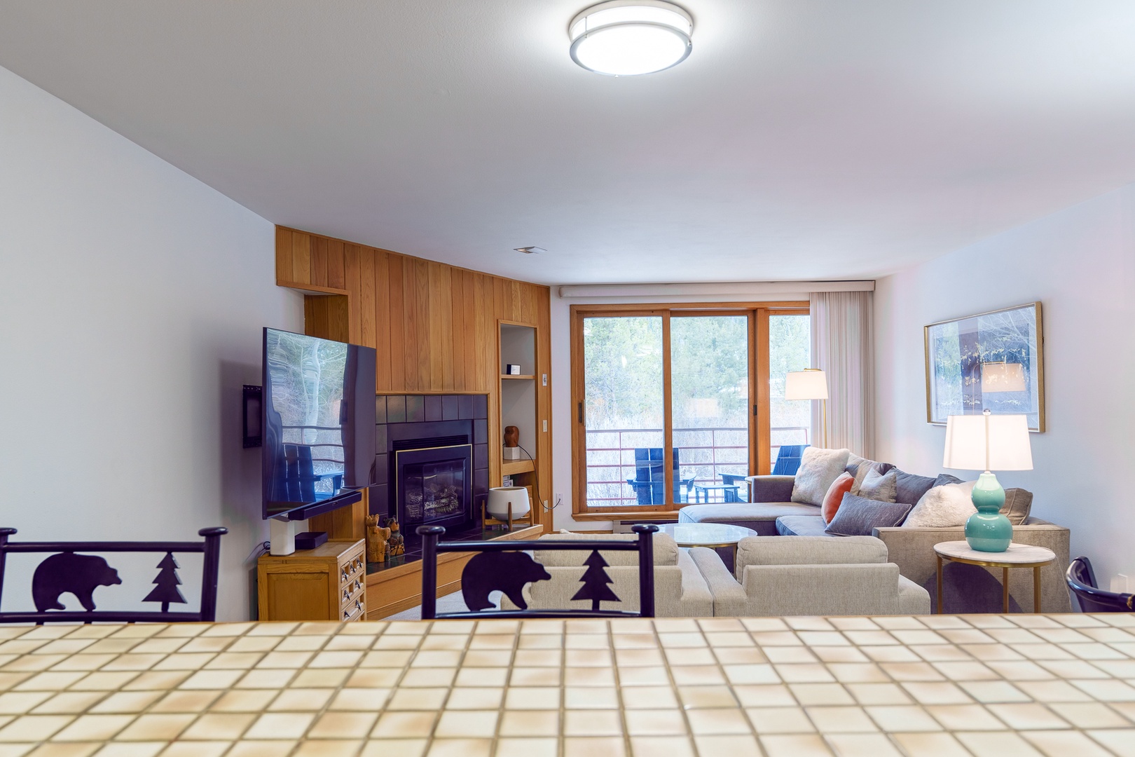 Unwind in your cozy living space with warm wood accents, a crackling fireplace, and mountain views through sliding doors.