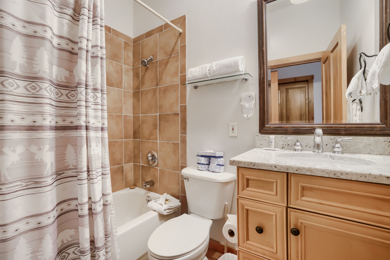 Your private bathroom features warm tan tile, a tub/shower combo, and a vanity with plenty of counter space—fresh towels and all the essentials ready for your stay.