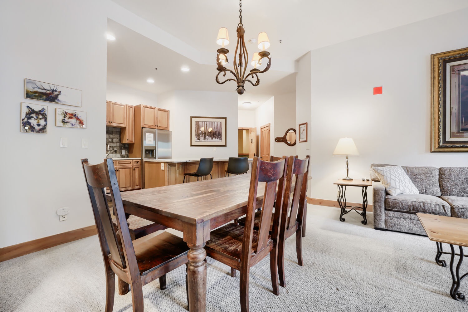 Open-concept living flows seamlessly from dining to kitchen to living area, with soaring ceilings and warm wood accents. Gather at the handsome wood table, then relax on the plush sofa for memorable evenings.