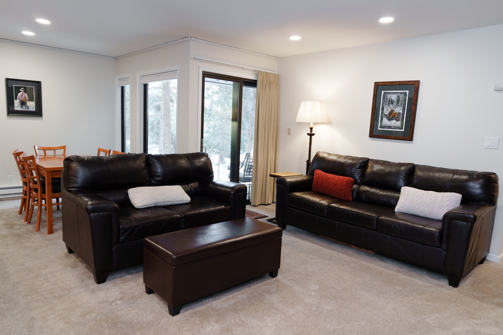 Relax in your spacious living area featuring comfortable leather sofas and dining space with natural light streaming through large windows.