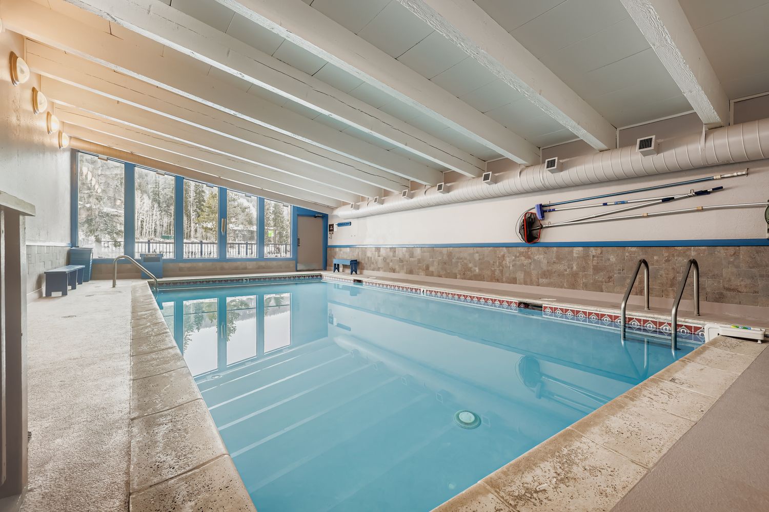 community indoor pool, complete with beautiful exposed beam ceilings and natural light streaming through large windows.