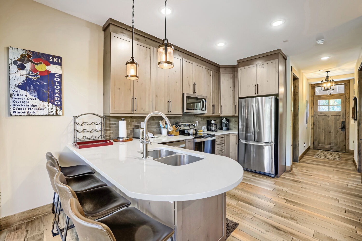 Gather around this inviting kitchen island with friends and family, where gleaming countertops, modern stainless steel appliances, and warm wood cabinetry create your perfect mountain retreat cooking space.