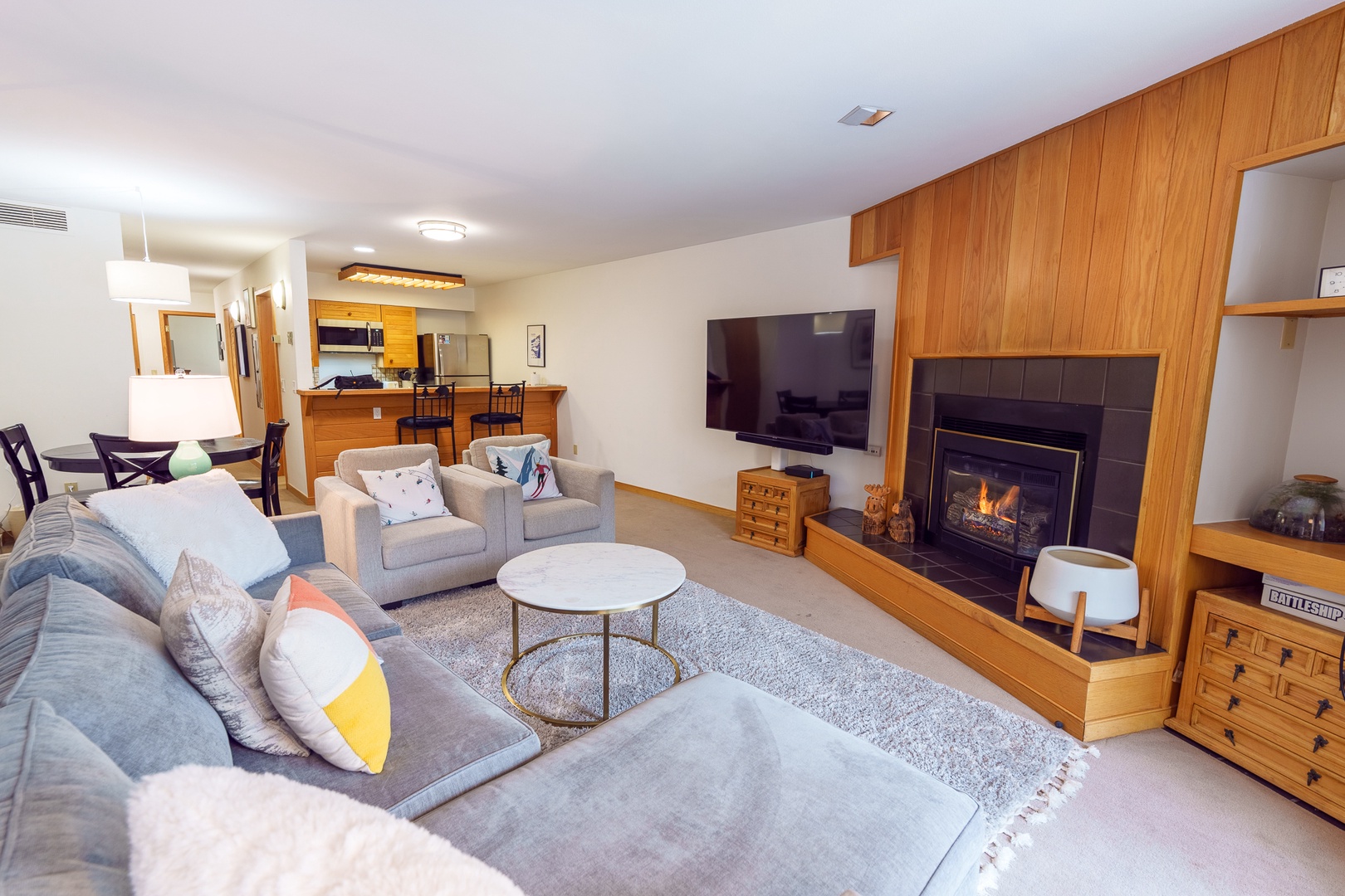 Sink into plush sofas by your crackling fireplace, where warm wood accents create the perfect mountain retreat atmosphere for cozy evenings.