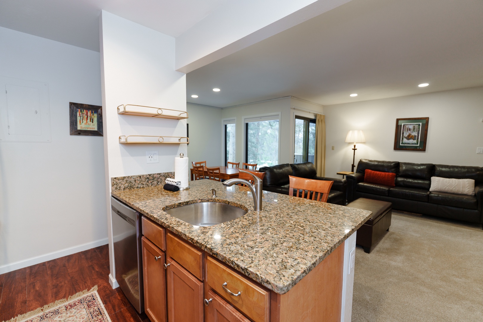 Relax in your spacious open-concept living area with granite kitchen island, leather seating, and natural light streaming through large windows.