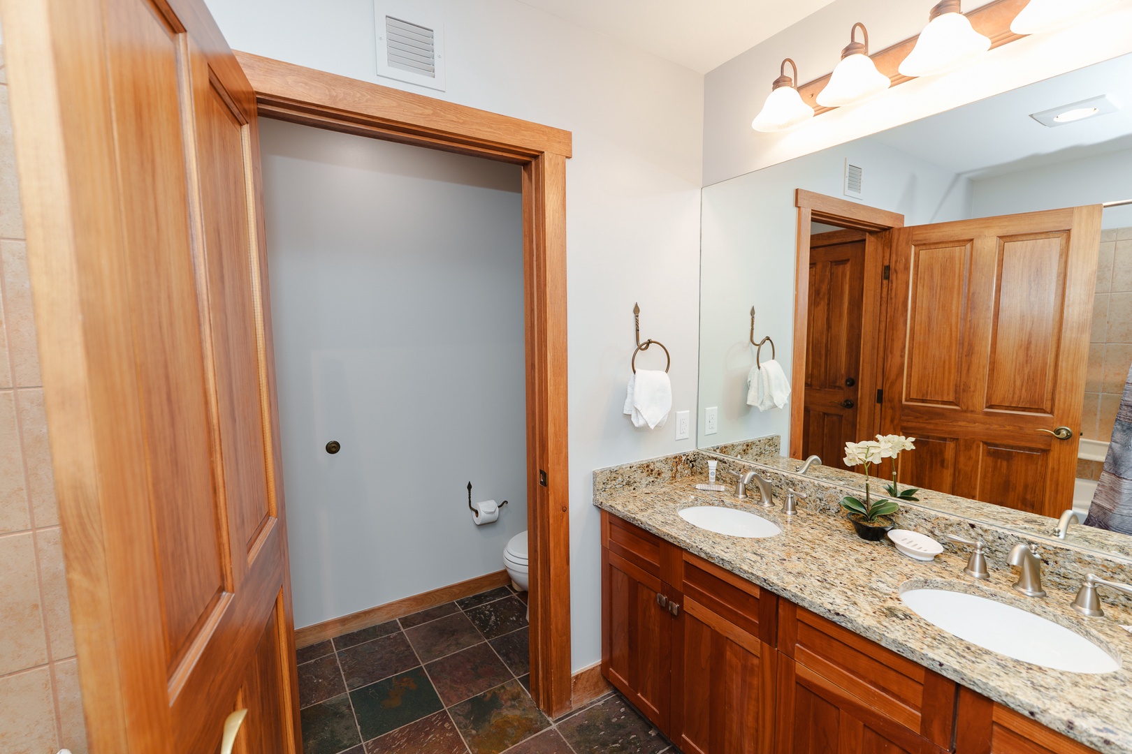 Your spacious bathroom features elegant granite countertops, dual sinks, and warm wood cabinetry for a luxurious retreat experience.