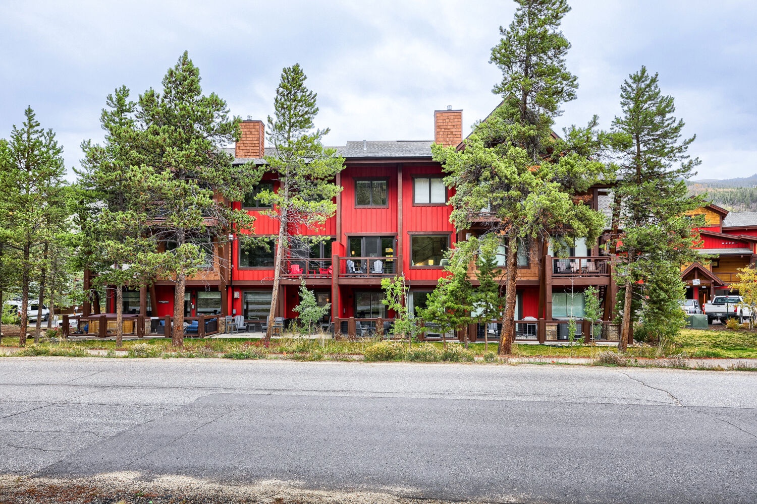 Distinctive red mountain lodge framed by pine trees, offering easy access to the surrounding natural landscape and nearby outdoor activities.