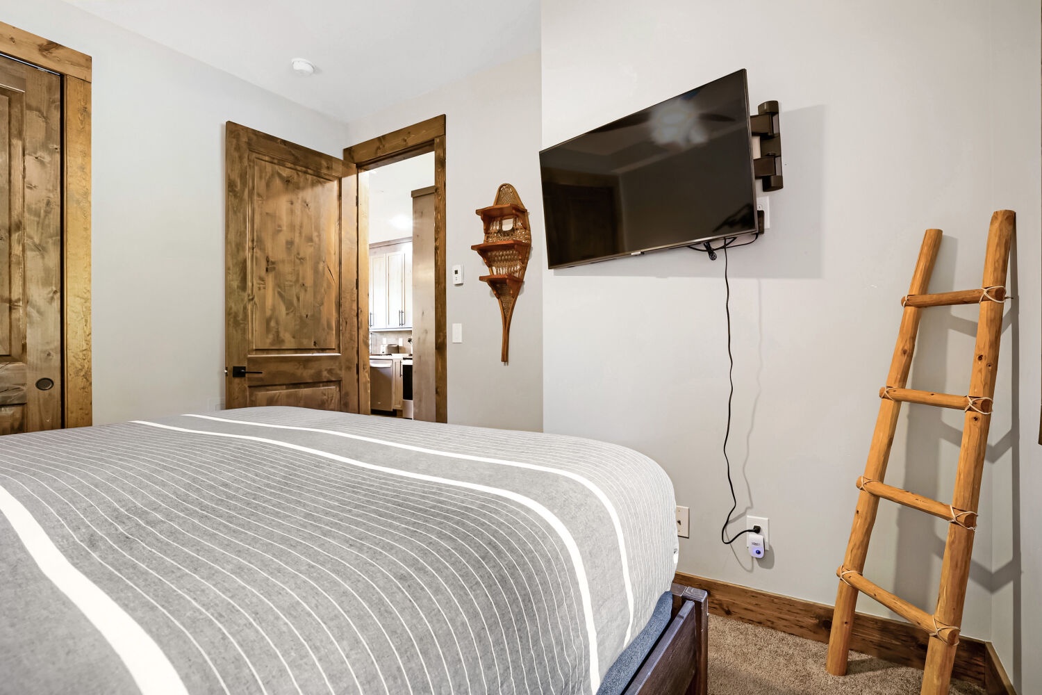 Your bright bedroom blends rustic charm with modern comforts—warm wood accents, a wall-mounted TV for your favorite shows, and a cozy bed dressed in crisp linens.