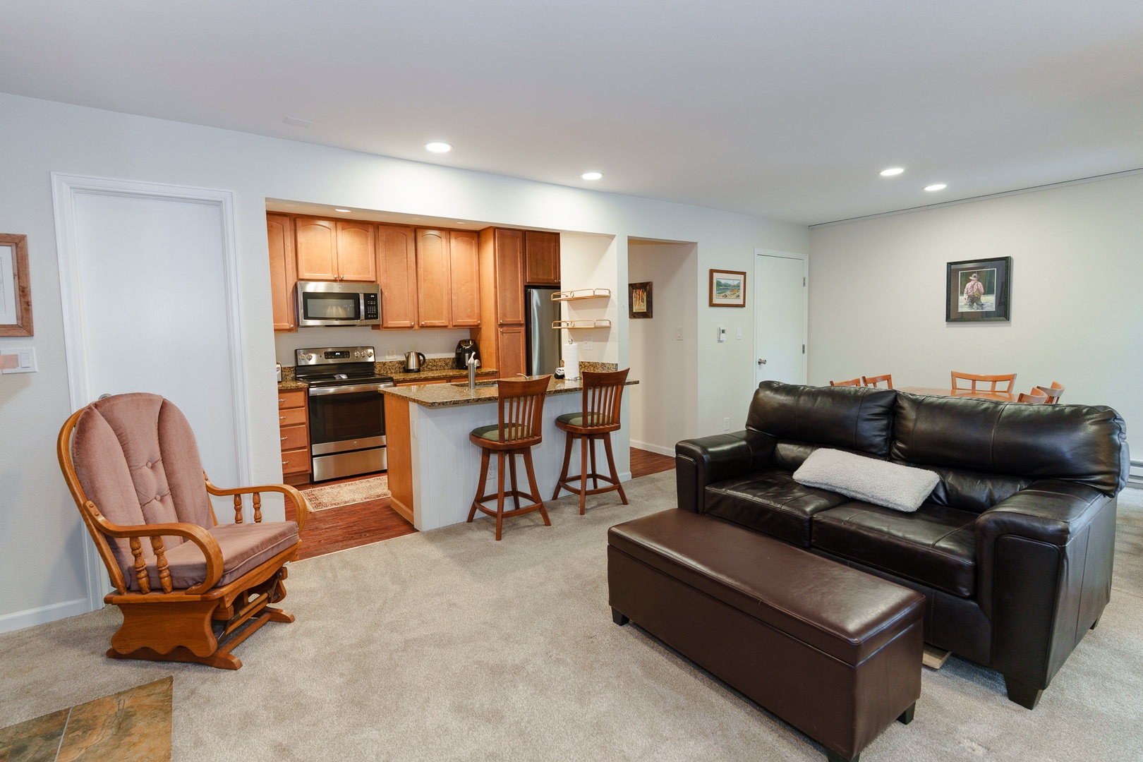 Relax in your spacious living area featuring comfortable leather seating and a fully equipped kitchen with modern appliances and breakfast bar for convenient dining.