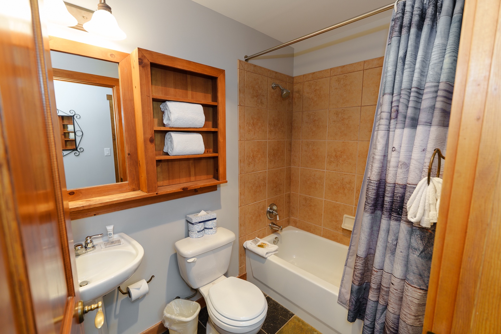 Your private bathroom features a relaxing tub-shower combo with thoughtful wood cabinetry and fresh towels waiting for your arrival.