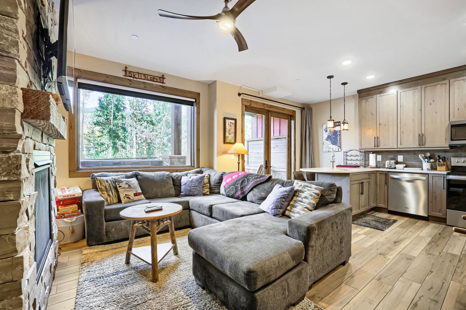 Sink into plush sectional seating as natural light floods your inviting living space, where rustic stone accents and modern comforts create your perfect mountain retreat.