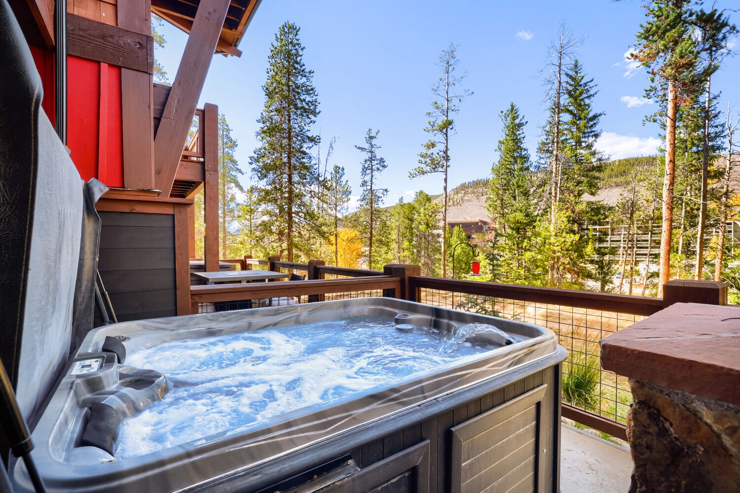 Mountain retreat with private hot tub on the deck, surrounded by towering pines and peaceful forest views.