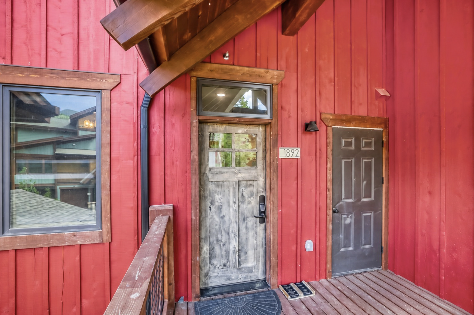This charming red building with rustic wooden trim and timber accents marks your arrival at unit 1827, featuring dual entry doors and a welcoming covered entryway.