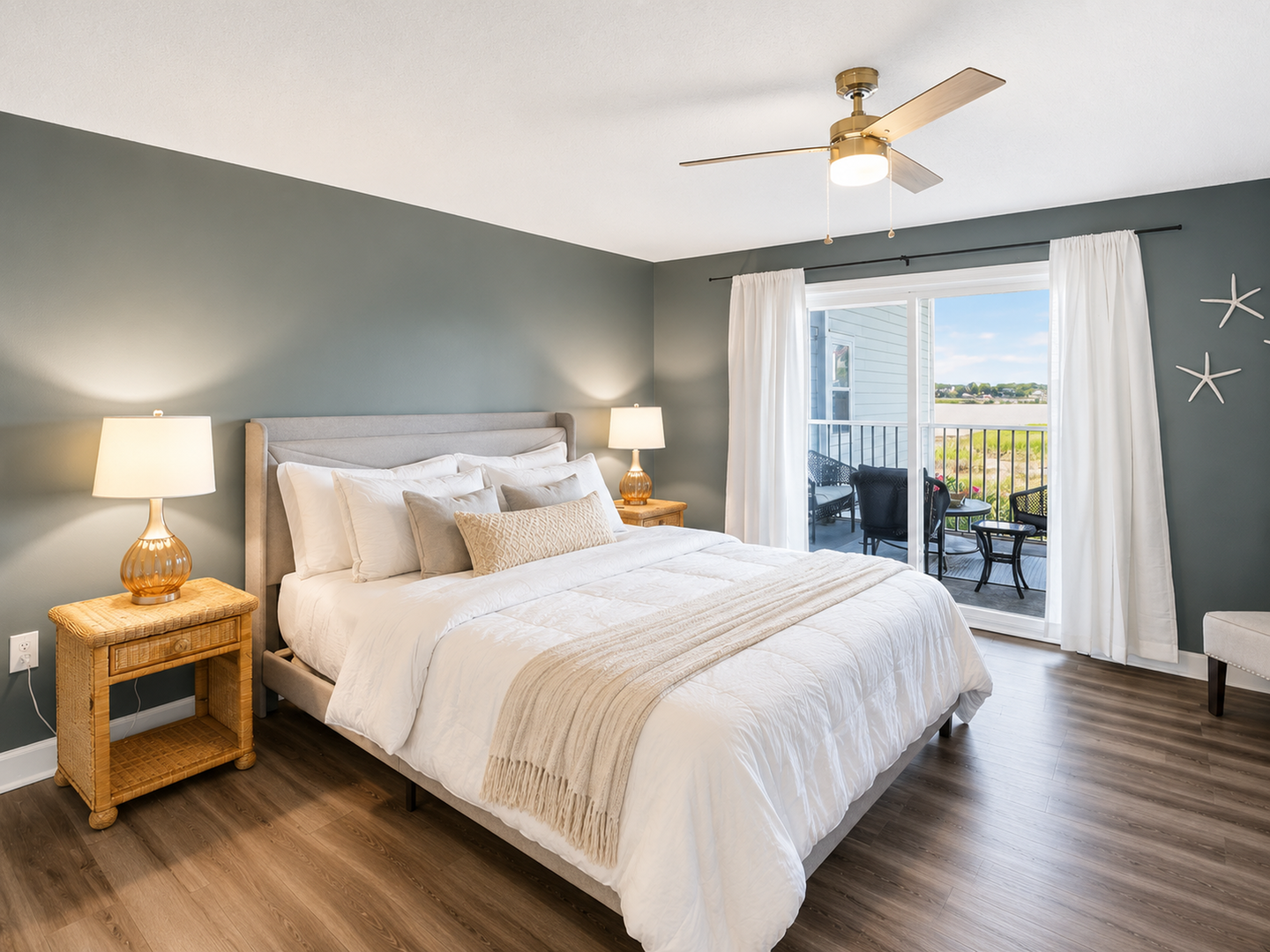 Relax in your serene bedroom with plush bedding, warm coastal accents, and a private balcony inviting you to unwind with peaceful water views.