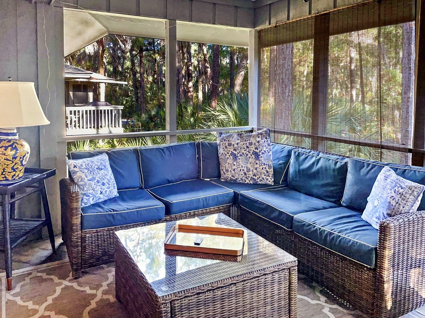 Relax on your screened porch with plush blue seating, tropical views, and gentle breezes filtering through bamboo shades.