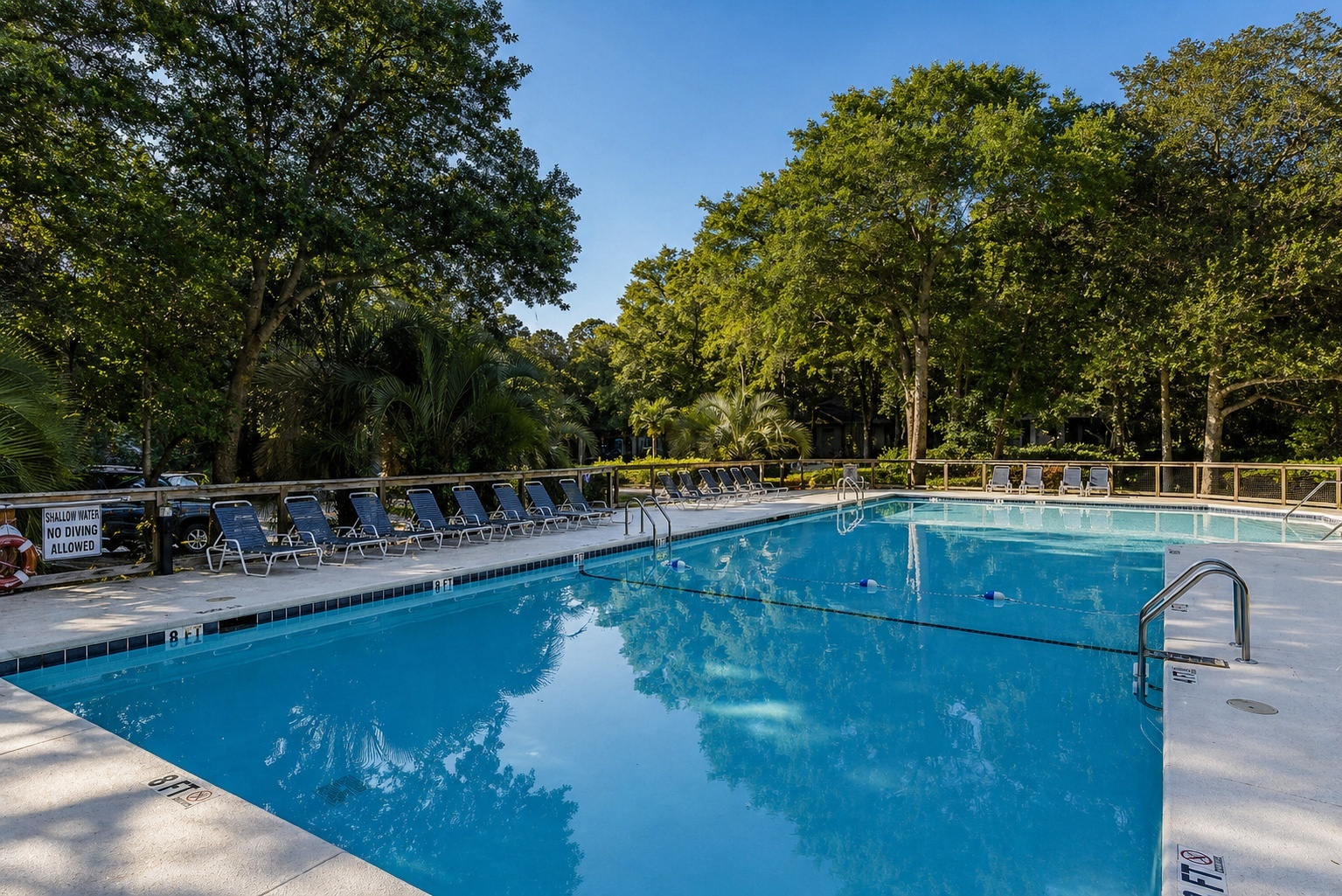 Sparkling pool surrounded by lush trees creates the perfect oasis for your afternoon swim and relaxation.