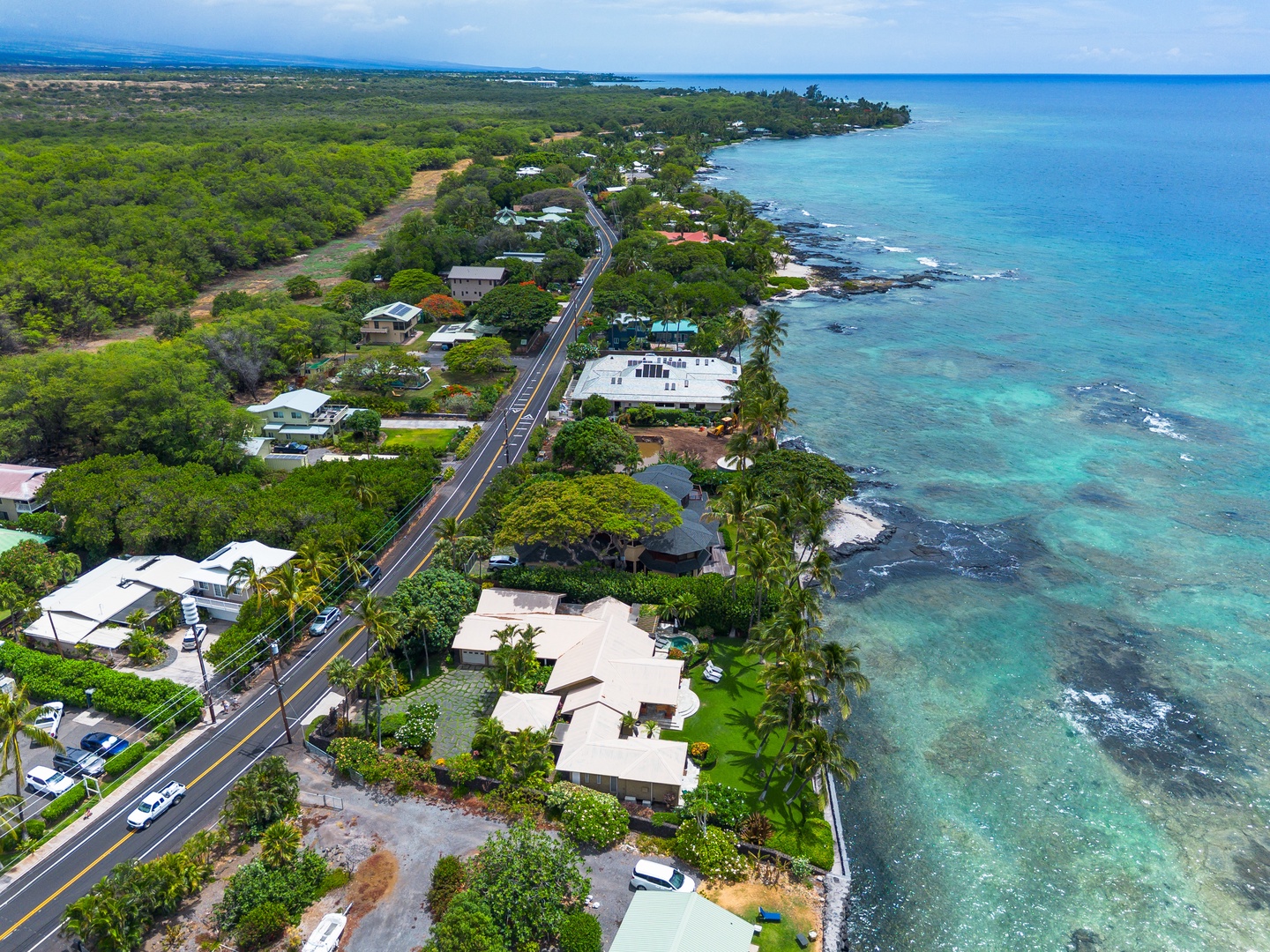 Aerial view of a coastal neighborhood nestled between lush tropical vegetation and stunning turquoise waters, with easy access to nearby beaches and natural landscapes.