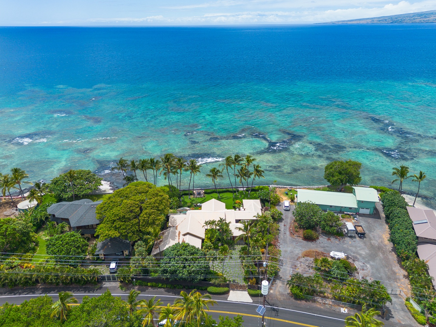 Oceanfront property nestled along pristine turquoise waters with nearby beach access, surrounded by lush tropical palms and gardens in a serene coastal setting.