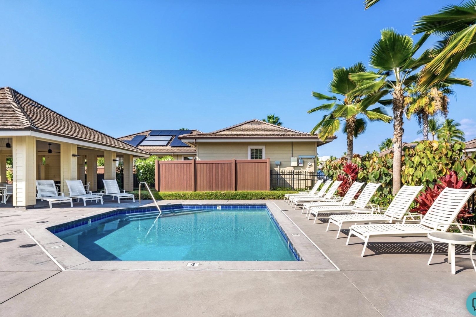 Sparkling community pool surrounded by tropical palms and lounge chairs creates your perfect Hawaiian retreat under endless blue skies.