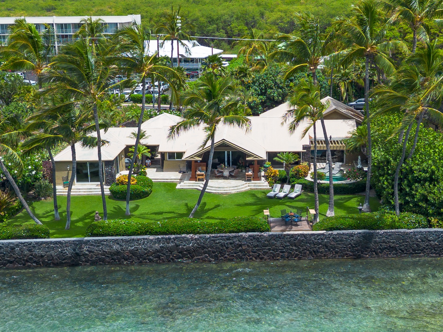 Puako Beach Drive - Beachfront property nestled in lush tropical landscaping with palm trees, offering nearby water access and a spacious lawn area.