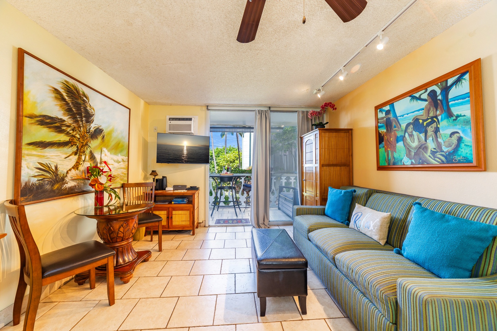 Unwind in your bright, tropical-inspired living space with island art, comfy seating, and doors opening to your private outdoor retreat.