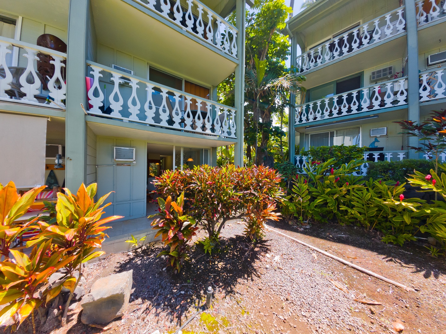 Multi-story property features distinctive white-railed balconies with tropical gardens nestled in the inner courtyard, creating a serene and private atmosphere.