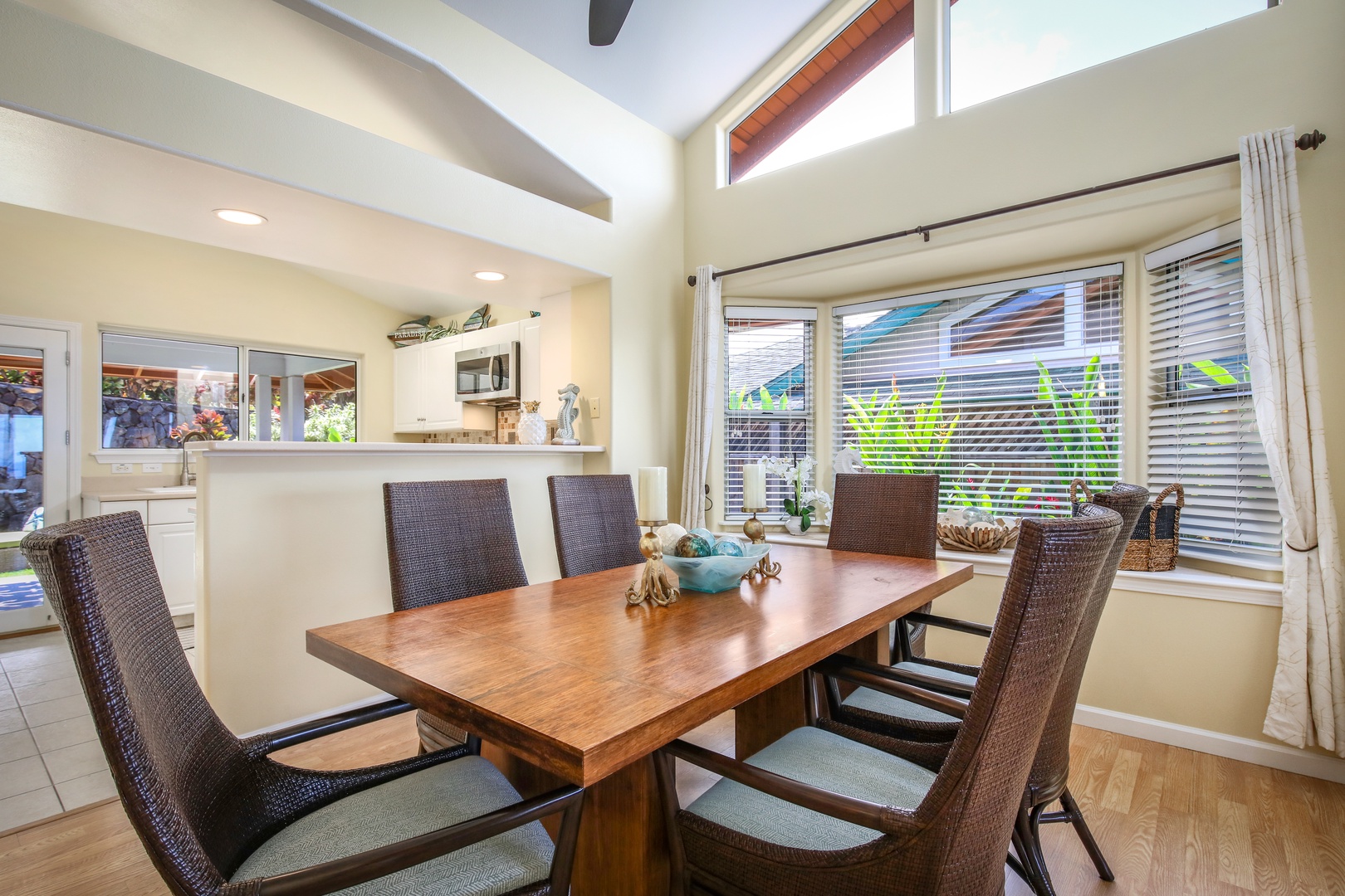 Gather around this elegant dining table with room for everyone. High ceilings and sunlight streaming through generous windows create a warm, open atmosphere perfect for your morning coffee or shared meals together.
