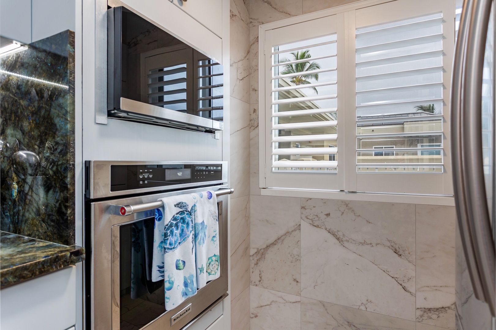 Your modern, well-equipped kitchen features stainless steel appliances and a bright, inviting atmosphere with natural light streaming through elegant shutters.