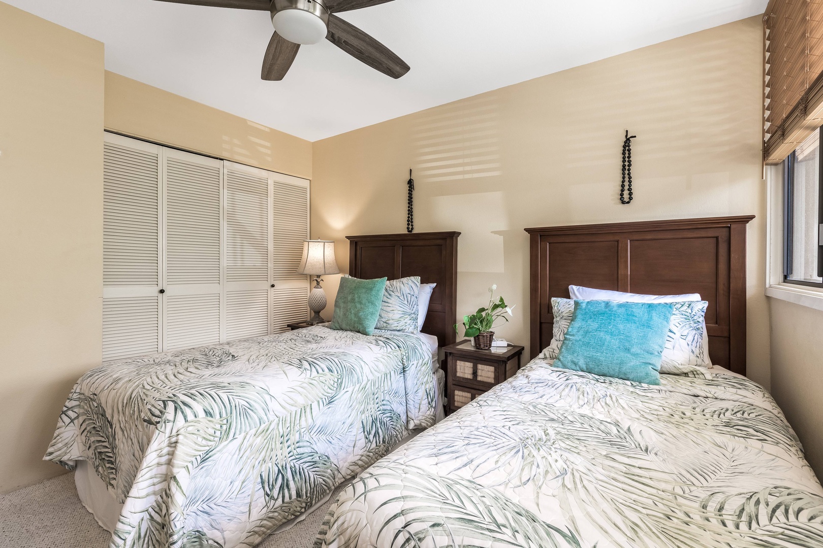 Your serene retreat awaits with two plush beds draped in tropical-print linens, where the gentle ceiling fan and soft morning light create the perfect setting for restful mornings and peaceful nights.