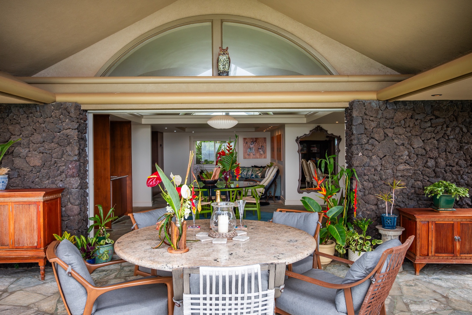 Step into your island retreat where lush tropical plants, natural stone walls, and breezy indoor-outdoor living blend seamlessly, inviting you to dine and unwind in paradise.